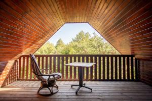 einen Tisch und einen Stuhl auf einer Holzterrasse in der Unterkunft Domek na Kaszubskiej z balią i kominkiem in Skoszewo