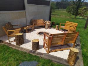 eine Terrasse mit Bänken und eine Feuerstelle mit Holzscheiten in der Unterkunft Camiño da Vieira in Padrón