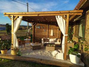 eine hölzerne Pergola mit einem Sofa und einem Tisch in der Unterkunft Camiño da Vieira in Padrón