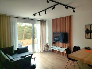 ein Wohnzimmer mit einem TV, einem Tisch und Stühlen in der Unterkunft Apartman SRNA, Vila JEZERO in Divčibare