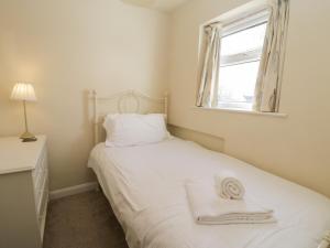 a bedroom with a bed with white sheets and a window at Cosy Cottage in Potto