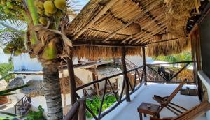 Habitación con balcón con palmeras y sillas. en Casa Sofia Holbox, en Isla Holbox