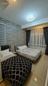 a bedroom with two beds and a brick wall at J&J Vacation Home@Novo8 Residence in Kampong Tambak