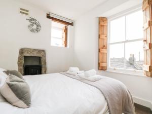 a white bedroom with a bed and a fireplace at Mole Cottage in Mousehole