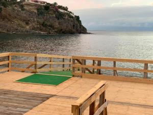 einen hölzernen Pier mit einer grünen Yogamatte auf dem Wasser in der Unterkunft Villa Stella Marina in Brucoli