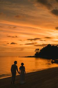 
two people walking on a beach near the ocean at Adang Island Resort in Ko Lipe
