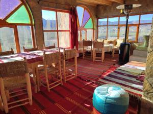 a dining room with a table and chairs and windows at Auberge restaurant Afoud in Agoudal