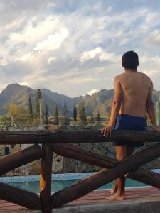 Un uomo seduto su una recinzione che guarda le montagne di Mirador de Montaña a Ciudad Lujan de Cuyo