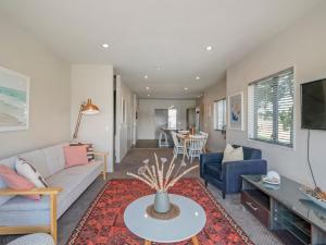 a living room with a couch and a table at Sunset Retreat - Matarangi Holiday Home in Matarangi