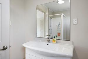 Baño blanco con lavabo y espejo en Sea La Vie - Russell Holiday Home, en Russell