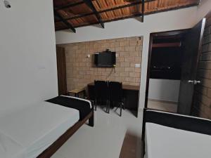 a room with a table and a tv on a wall at Minimal Poshtel in Mysore