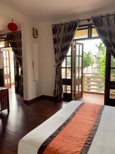 a bedroom with a large bed and large windows at The Muse House in Hoi An