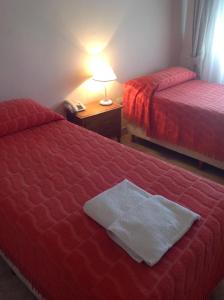 Habitación con 2 camas y mesa con lámpara. en Hotel San Carlos en Termas de Río Hondo