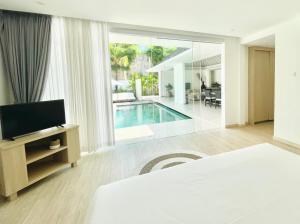 a bedroom with a bed and a tv and a swimming pool at Alami Luxury Villa in Seminyak