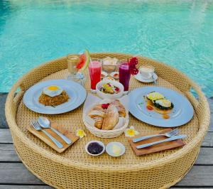 a table with breakfast foods and drinks on a table by a pool at Alami Luxury Villa in Seminyak