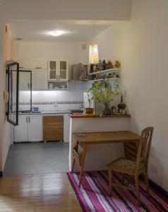 ブエノスアイレスにあるDepartamento en San Telmoの白いキャビネットと木製テーブル付きのキッチン