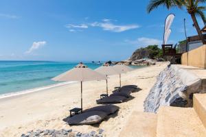 - une rangée de chaises longues avec parasols sur une plage dans l'établissement Rummana Boutique Resort - SHA Plus, à Lamai
