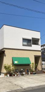 un edificio con un toldo verde delante de él en 森のカフェ, en Beppu