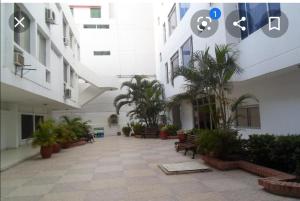 une cour d'un bâtiment avec des palmiers et des bancs dans l'établissement Apartamento amoblado en Bocagrande - Cartagena de Indias, à Carthagène des Indes