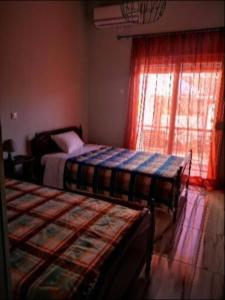 1 dormitorio con 2 camas y ventana en ΧΑΡΗΣ ROOMS en Kritharia