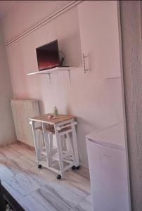 ΧΑΡΗΣ ROOMS في Kritharia: طاولة بيضاء صغيرة في غرفة مع تلفزيون على الحائط
