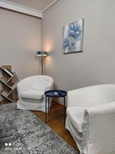 ein Wohnzimmer mit 2 weißen Stühlen und einem Tisch in der Unterkunft Cozy apartment near the sea in Palaio Faliro in Athen