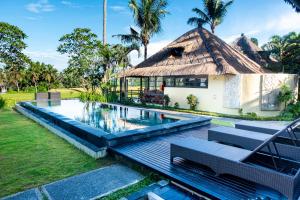 a house with a swimming pool and a thatched roof at Lodtunduh Sari in Ubud
