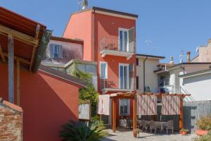 a red building with a balcony and a patio at La corte dei tre in Torre del Lago Puccini