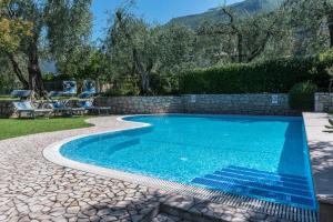 a swimming pool in a yard with a stone wall at Residence La Pergola monolocale due in Malcesine