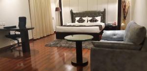 een slaapkamer met een bed, een stoel en een tafel bij Grand Geet Hotels in Kānpur