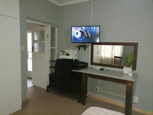 a room with a desk with a mirror and a television at Adirondack Inn in Estcourt