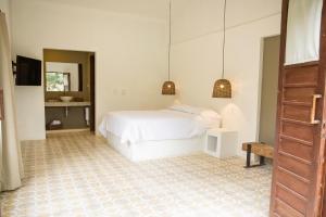 a white bedroom with a bed and a mirror at La Frontera in Chinchiná