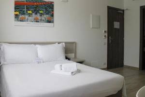 una camera da letto con un grande letto bianco con asciugamani di Best Quality Hotel Politecnico a Torino