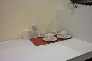 a tray with cups and plates and a bottle of water at Summer Oscar Boutique Hotel in Subang Jaya