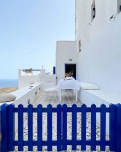 een blauw hek voor een tafel op het strand bij Serifos White in Serifos Chora