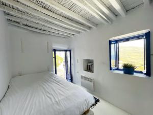 a white bedroom with a bed and a window at Serifos White in Serifos Chora