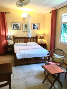 1 dormitorio con 1 cama, mesa y sillas en La Reine Creole, en La Gaulette
