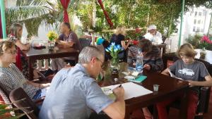 un grupo de personas sentadas en mesas en un restaurante en Daphne Hotel, en Mahabalipuram