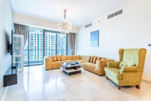 un soggiorno con divano, sedie e lampadario pendente di Icon Casa Living - Trident Grand Residence a Dubai