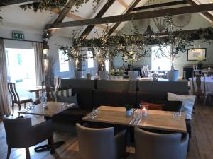 a restaurant with wooden tables and chairs and windows at The Farmhouse at Bodnant Welsh Food in Conwy