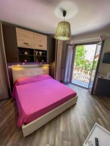 ein Schlafzimmer mit einem rosa Bett und einem großen Fenster in der Unterkunft La Casa del Poeta in Taormina