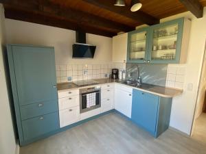 a kitchen with blue cabinets and a sink at Eckwarderhörne Objekt A 2 in Großwürden