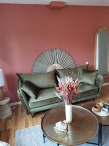 a living room with a green couch and a table with flowers at * LE CHAMARELLE * Hyper Centre Auray * in Auray