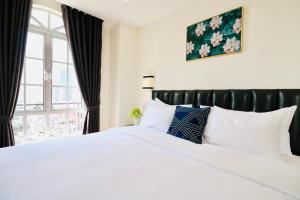 a bedroom with a large white bed with a window at Mettavary Hotel in Phnom Penh