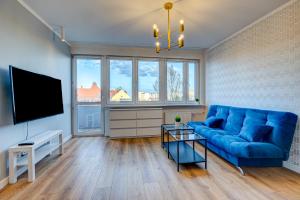 a living room with a blue couch and a flat screen tv at Apartament Szczecin Kobalt - Urząd Miasta in Szczecin