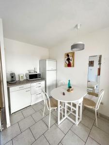 a kitchen with a white table and chairs in a room at Cap d'Agde Antinea, Plage Rochelongue, Piscine et Parking in Cap d'Agde