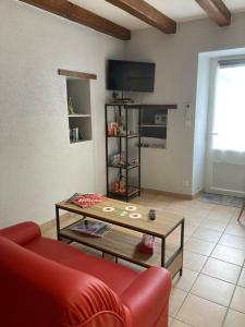 ein Wohnzimmer mit einem roten Sofa und einem Couchtisch in der Unterkunft Le petit monas in Civaux