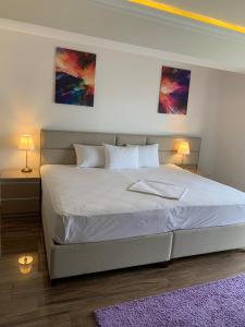 a bedroom with a large white bed with two lamps at White Tower Mamaia Prestige Apartments in Mamaia