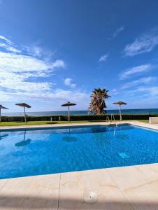 basen z parasolami i oceanem w obiekcie Mijas Beach Penthouse w mieście Sitio de Calahonda