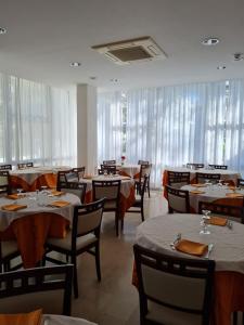 a dining room with tables and chairs and windows at Hotel Marconi Miramare in Rimini +44 photos